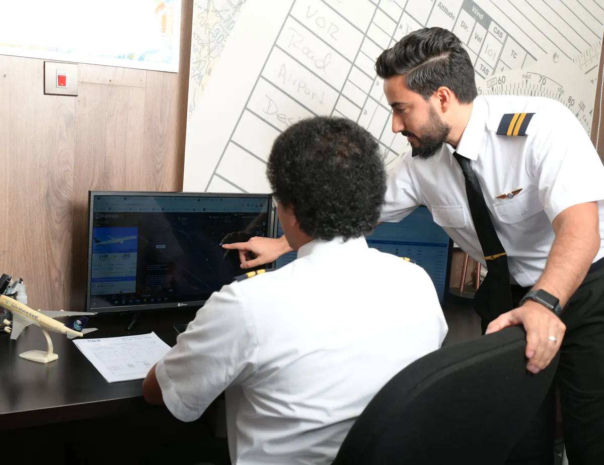 Instructor guiding a dispatch trainee through live flight tracking