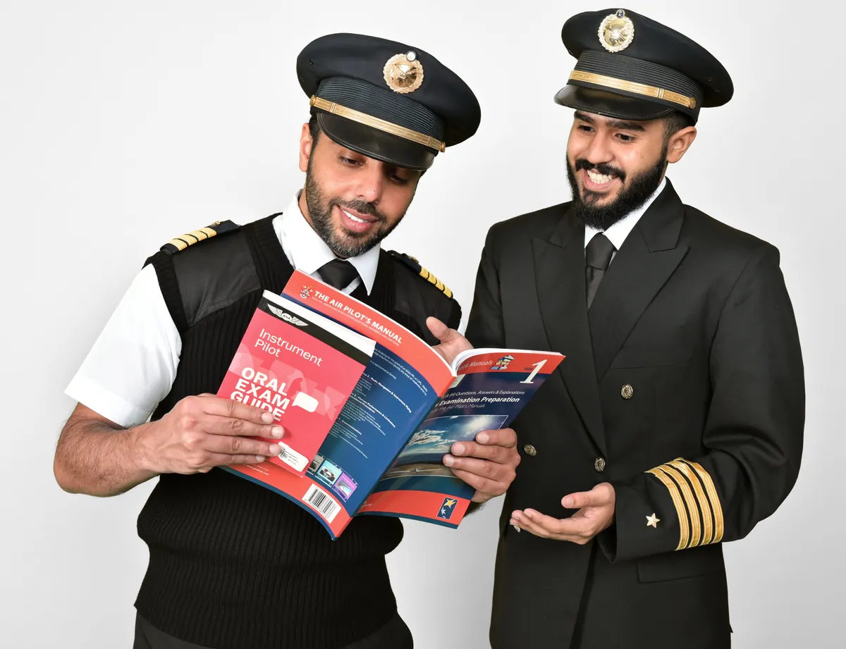 Two captains reviewing pilot exam preparation manuals